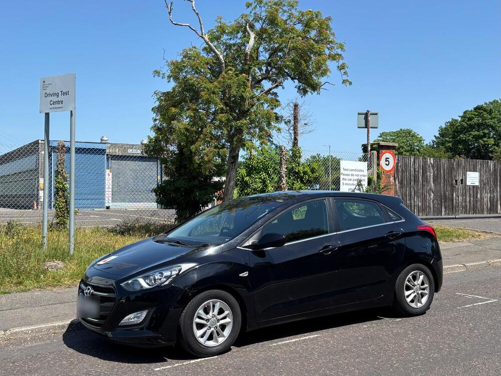 A black Hyundai i30, the same model Ian teaches in, parked outside Poole driving test centre