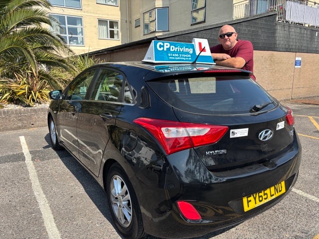 CP Driving's black Hyundai i30 with the teal CP Driving board on the roof, parked in Poole